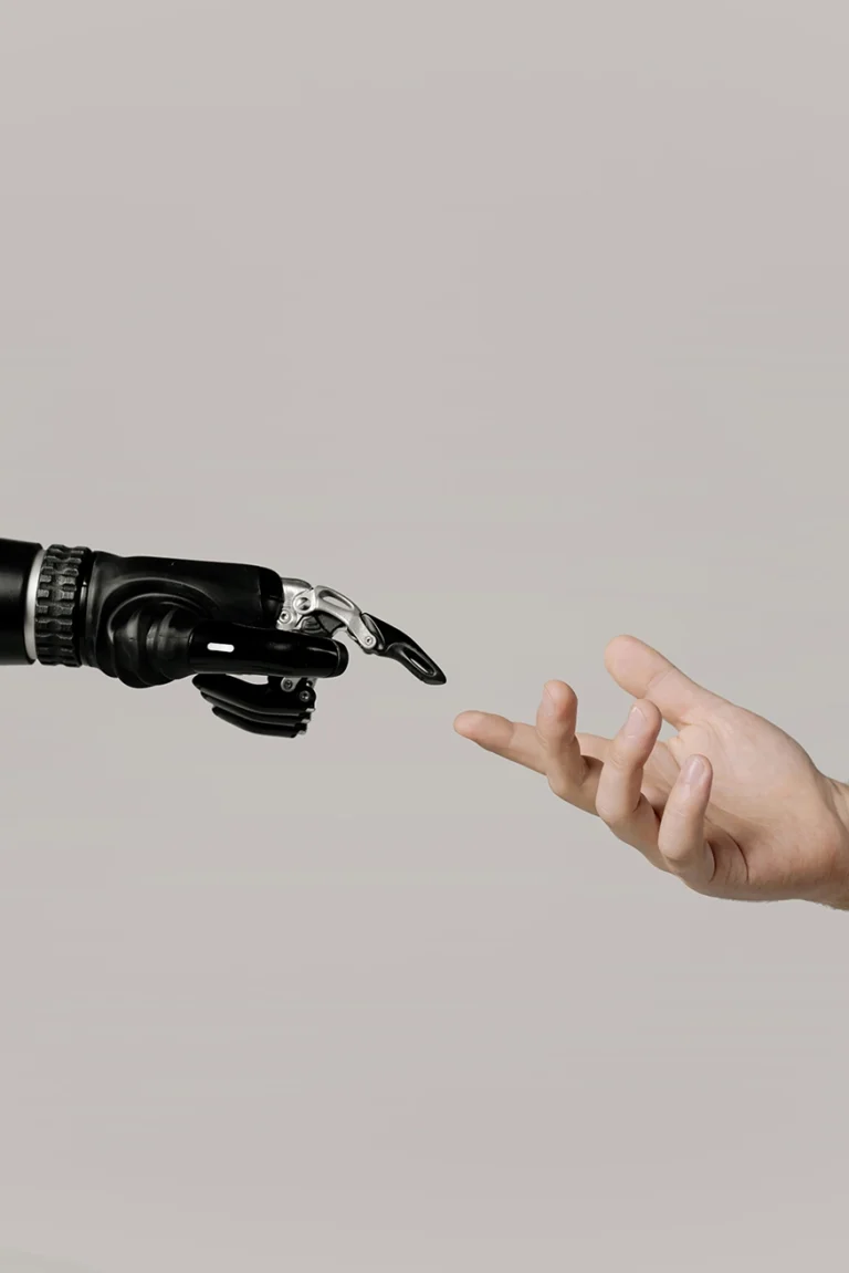 Ihmisen käsi kurottaa kohti robottikättä, symboloiden ihmisen ja tekoälyn yhteistyötä